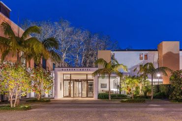 Entrance of Terra Nostra Garden Hotel at twilight with palm trees and illuminated facade.