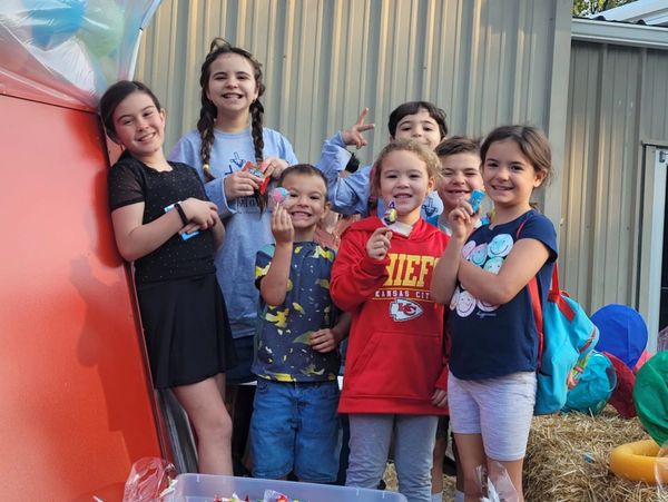 A group of happy children showing off medals outdoors.