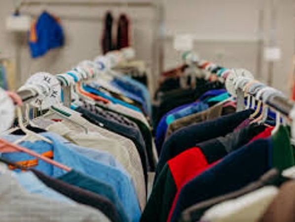 Clothes of various colors hanging on a rack in a store.