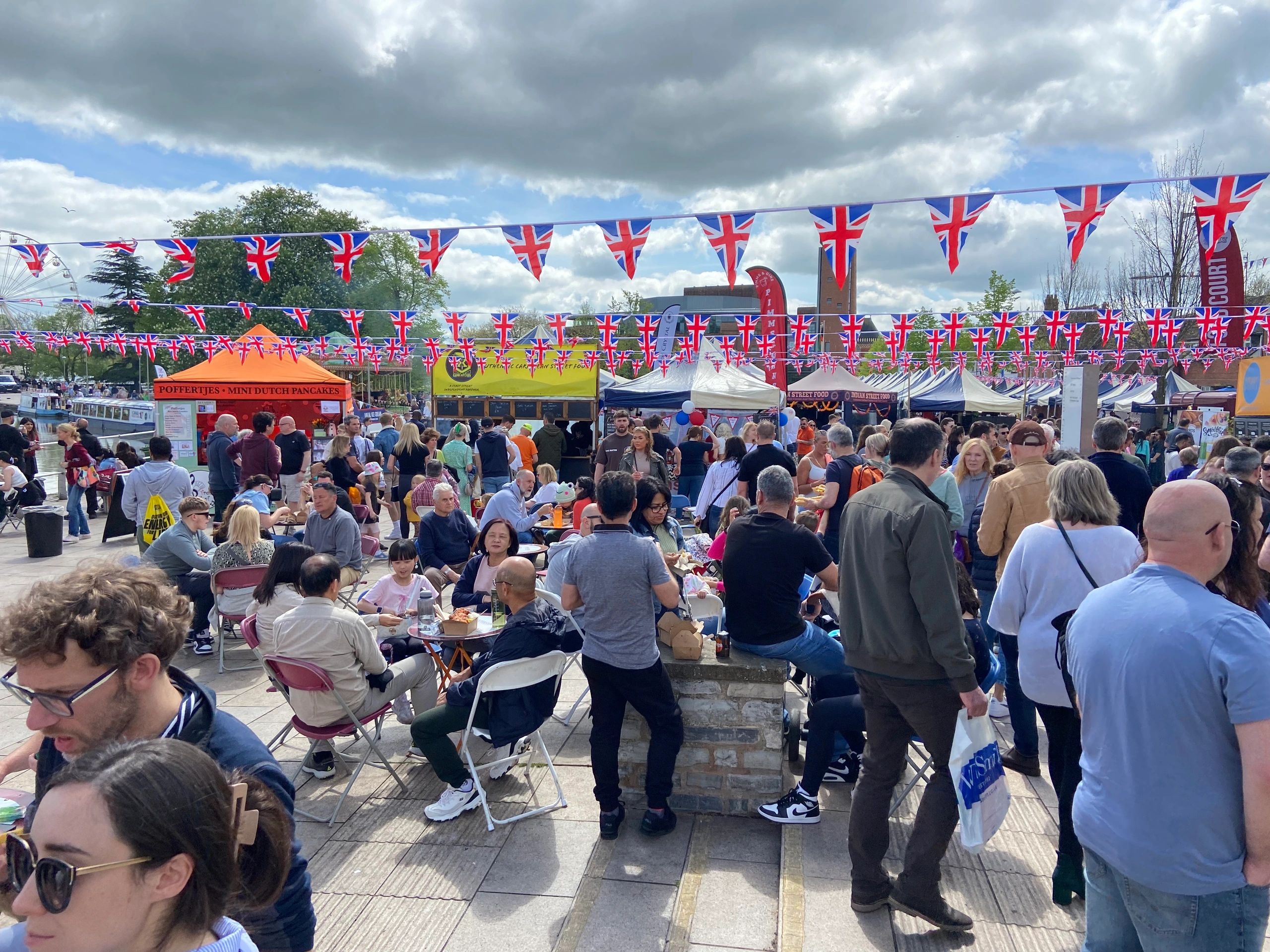 Crowded outdoor festival with Union Jack flags and food stalls.