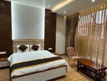 Modern bedroom with wooden flooring and large window.