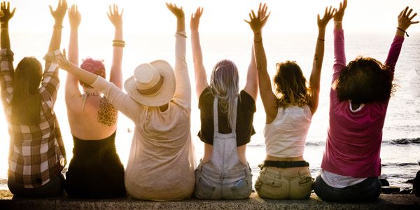 Photo of multiple women from behind holding their arms up in clebration