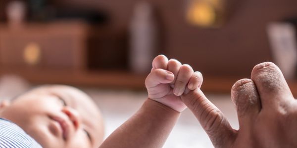 Photo of an infant holding its mother's finger