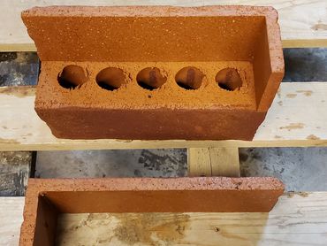 Two orange bricks with L-shaped edges on wooden pallets.