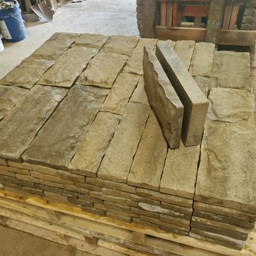 Stacked rectangular stone bricks on a wooden pallet in a workshop.
