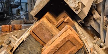 Clay bricks on a conveyor belt inside a brick manufacturing facility.