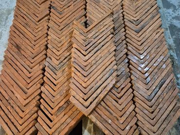 Stacked red bricks arranged in a V-shaped pattern on a wooden pallet.