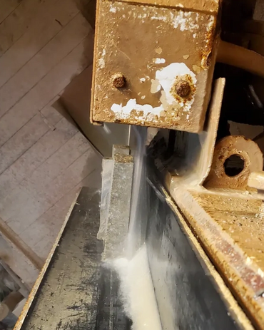 Close-up of a stone cutting machine slicing through a slab with water cooling.