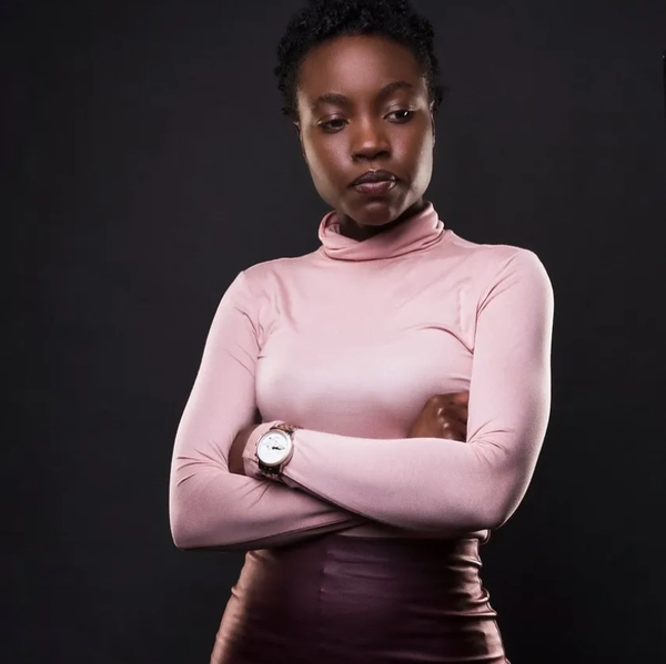 A woman in a pink turtleneck with arms crossed.