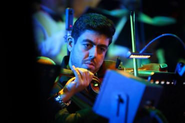 Man playing violin in a dimly lit setting.