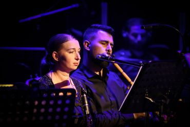 Two musicians performing on stage under blue lighting.