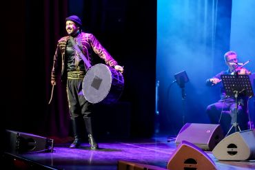 Musicians performing dabkeh on stage with traditional drum and violin