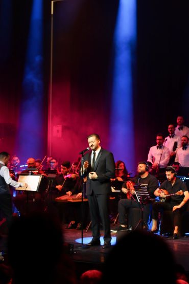 Alaa Khuzam performing with orchestra and choir on stage.