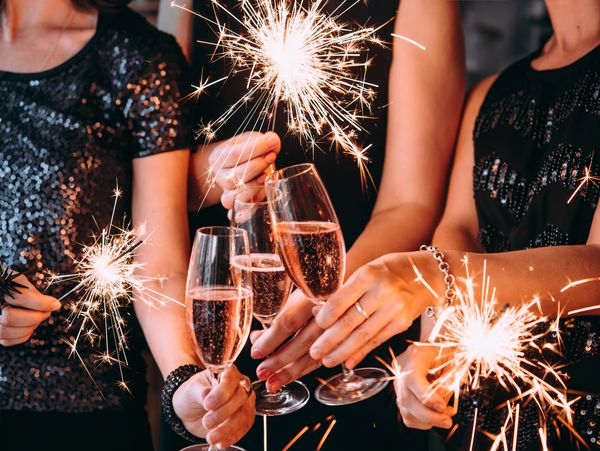 Friends celebrate Christmas or New Year party with Bengal lights and rose champagne.