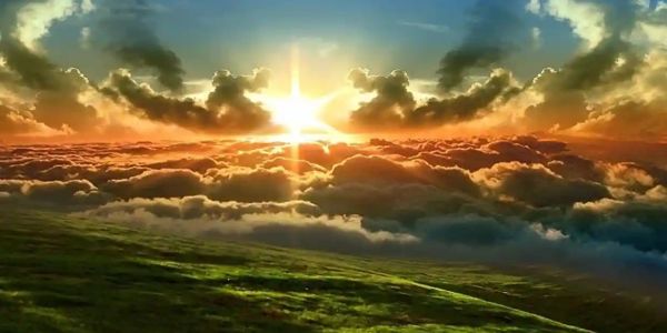Sunset over a green hillside with dramatic clouds.