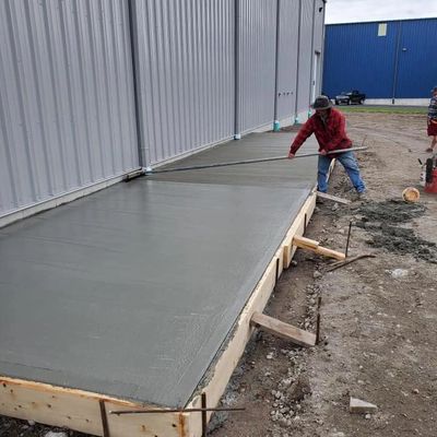 Contractor finishing poured concrete outside a commercial building—professional concrete services.
