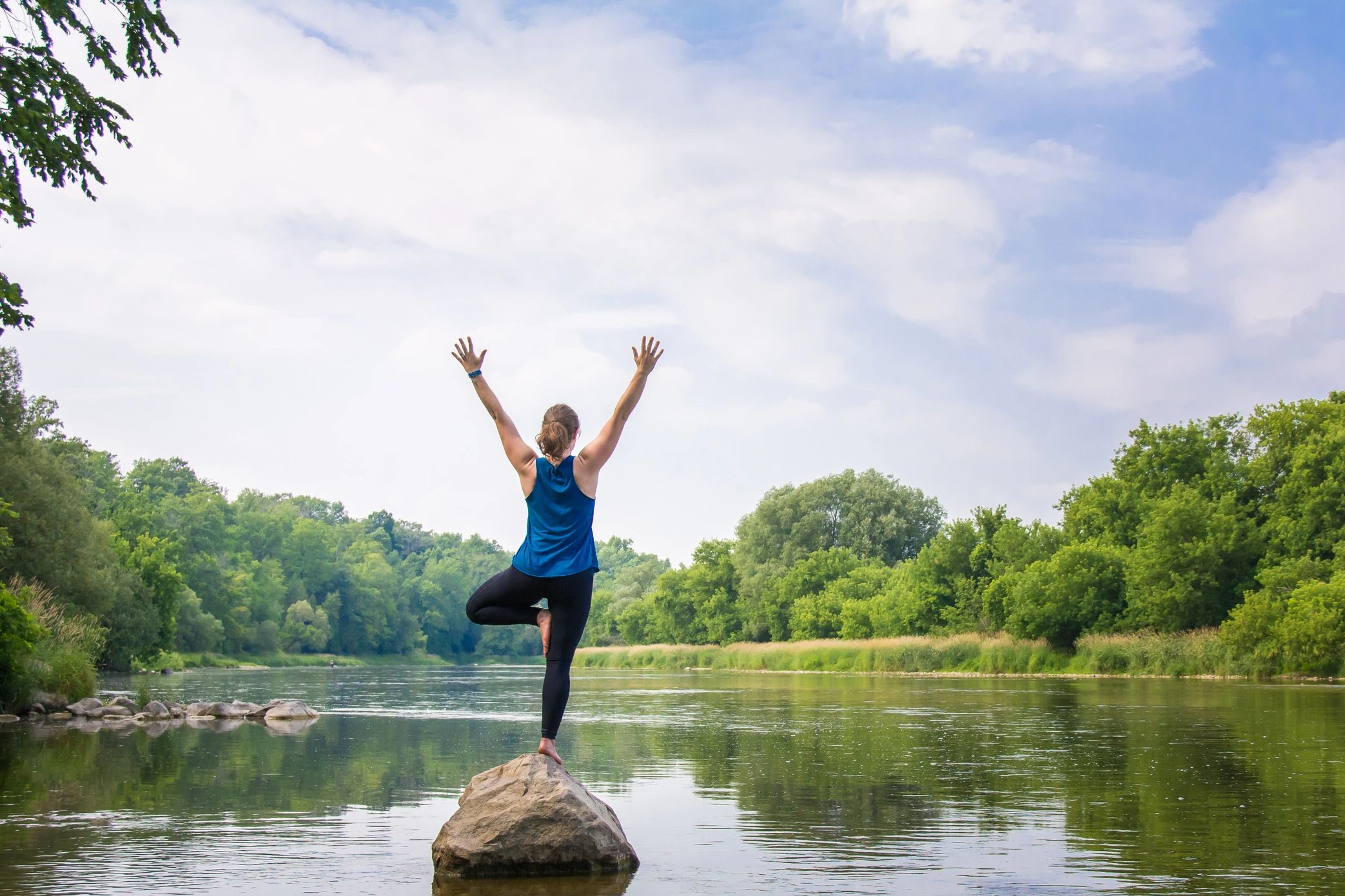 Waterloo Personal trainer and Yoga retreat teacher, Meagan is standing on a rock in a river.