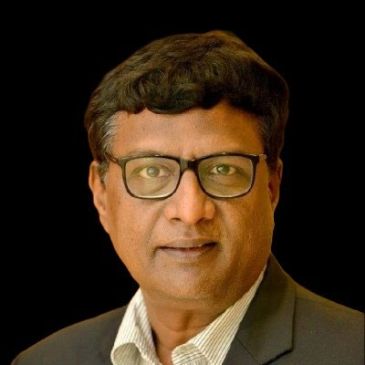 Portrait of a man wearing glasses and a suit against a black background.
