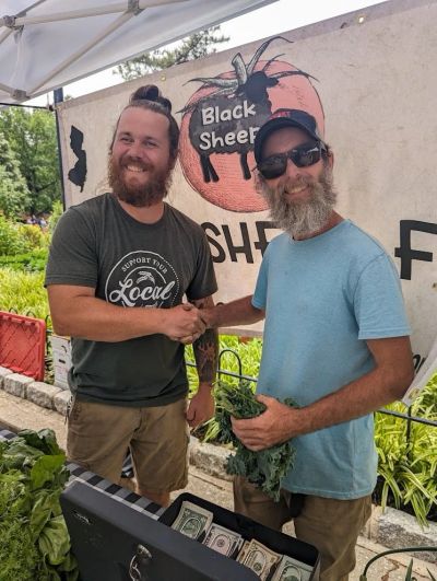 Two men shaking hands at a market stall.