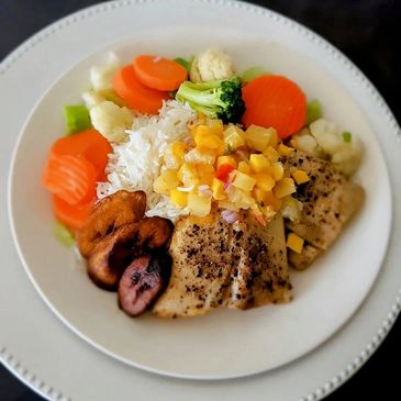 A colorful plated meal with fish, rice, vegetables, and plantains.