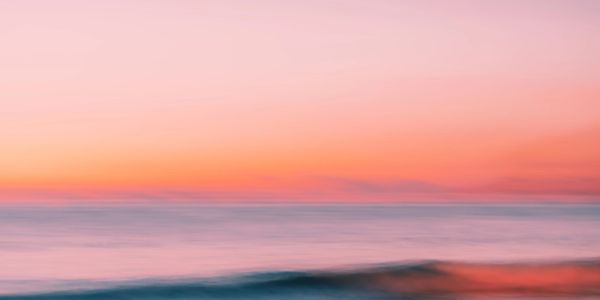 A serene ocean view at sunset with soft waves and vibrant colors.