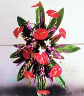 Tropical custom floral spray for Celebration of Life ceremonies. Orchids, Ti leaves and anthuriums. 