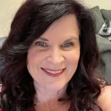 Smiling woman with dark curly hair.