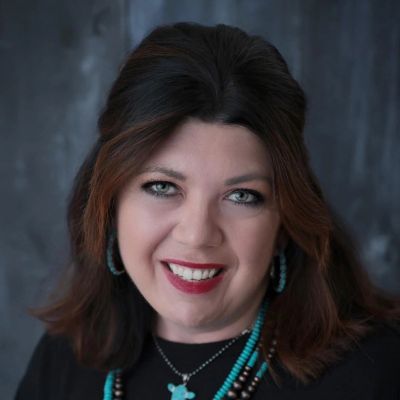 Smiling woman with turquoise jewelry and dark hair.