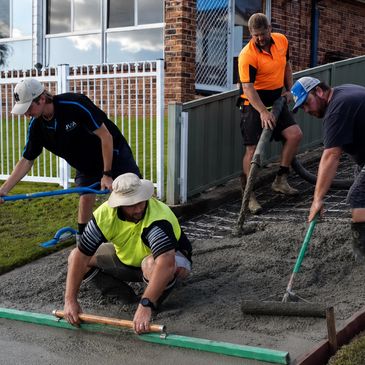 Four men working on pouring and smoothing concrete.