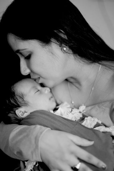 A tender moment of a mother kissing her sleeping baby, capturing pure love.