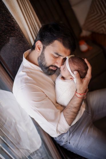 A tender moment between a father and his newborn baby wrapped in a soft blanket.