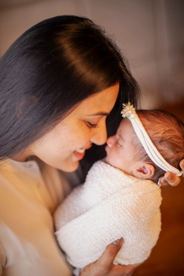 A mother lovingly gazes at her swaddled newborn baby.