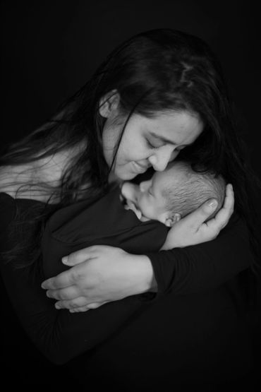 A mother tenderly embraces her sleeping newborn, sharing a quiet moment.