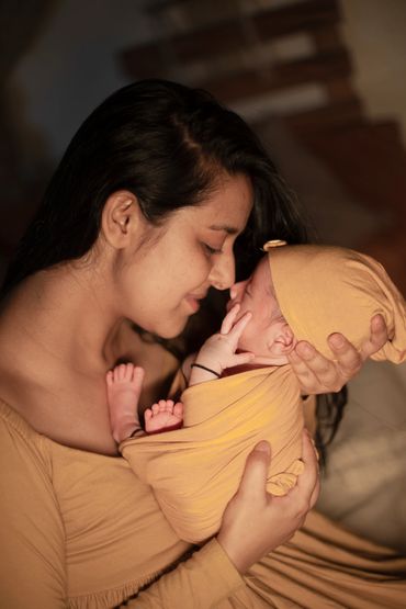 A mother lovingly cradles her newborn wrapped in a yellow blanket.