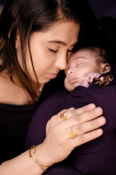 A mother lovingly holds her sleeping baby close to her.