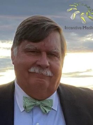 Man in suit with green bow tie smiling.
