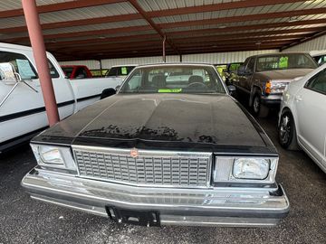 A vintage black car parked under a metal roof.