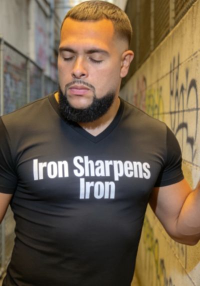 Man with a beard wearing a black shirt that says 'Iron Sharpens Iron'.