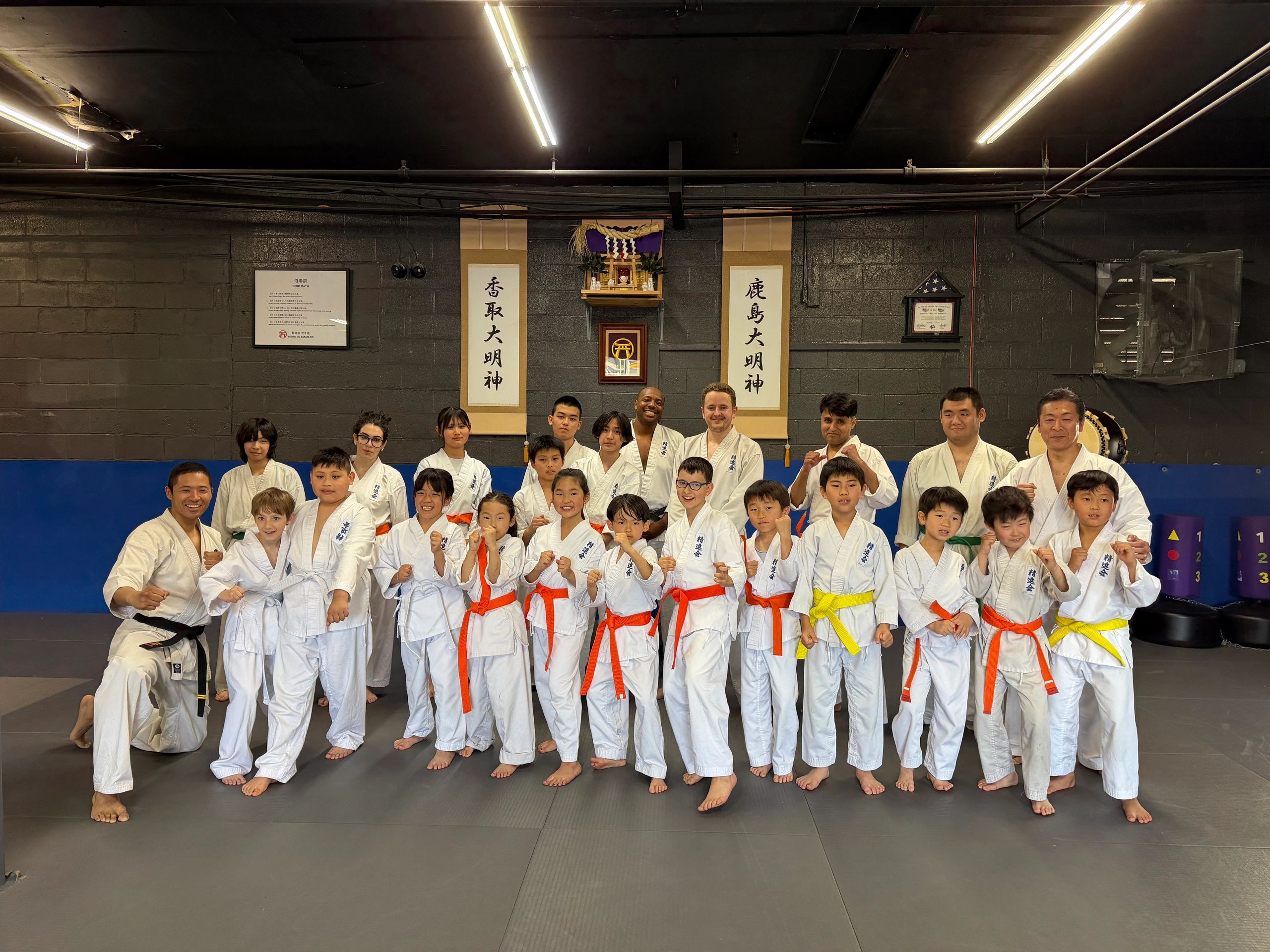 A diverse group of karate students and instructors posing in a dojo.