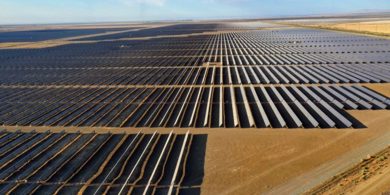 A vast solar farm with rows of solar panels in a desert landscape.