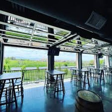Open-air seating area with stools overlooking a green landscape.