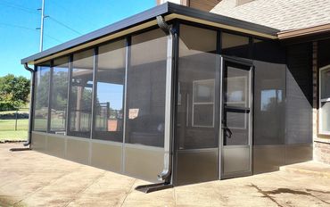 An aluminum screen room in bronze with kick panels at the bottom and a doggy door.