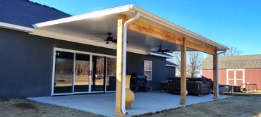 White insulated patio cover with dual fan installation and cedar posts and beams.