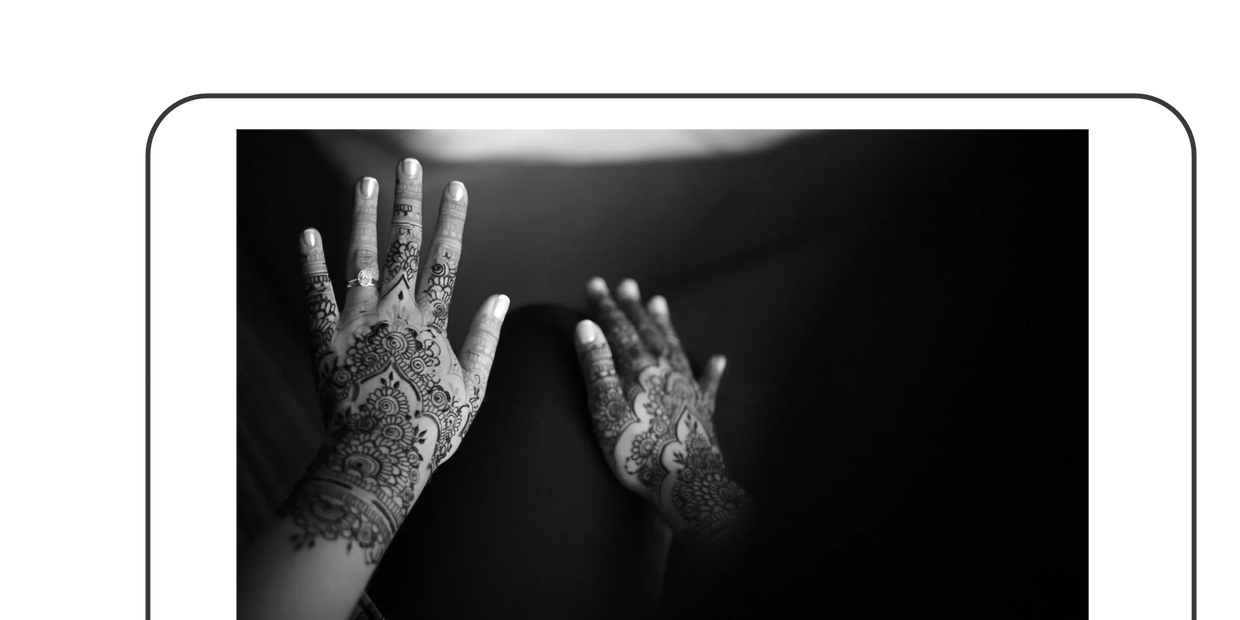 Hands adorned with intricate henna designs and an engagement ring.