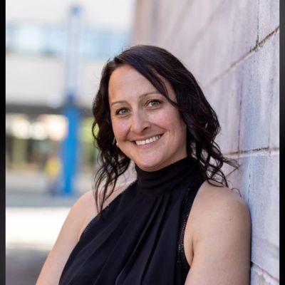 Smiling woman leaning against a wall.