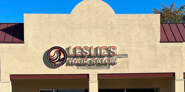 Leslie's Hair Salon sign with a silhouette logo on a beige building.