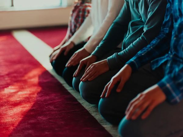 People sitting and praying on a red carpet.