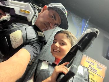 Two people wearing laser tag vests and holding laser guns.
