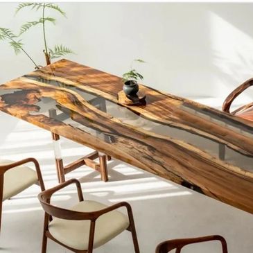 Elegant wooden dining table with glass inlay and modern chairs in sunlight.