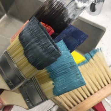 Multiple paintbrushes dipped in various paint colors.